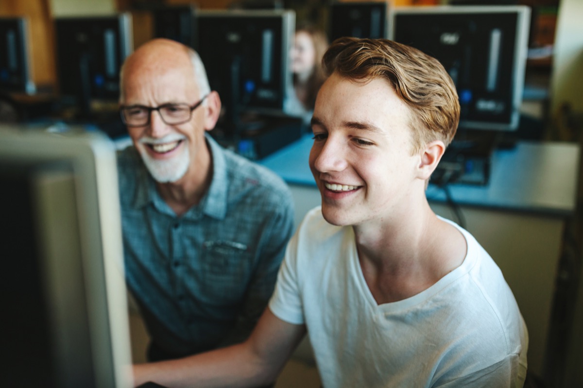 A teacher and a student smiling together at a computer